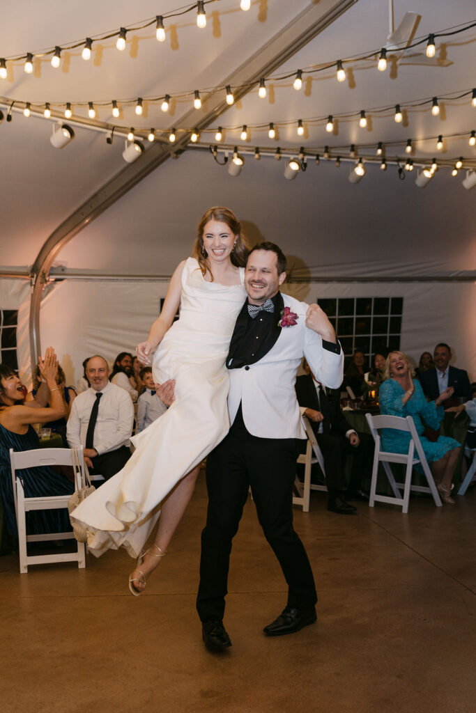 Fun reception moment as the groom lifts the bride on the dance floor at a Colorado garden wedding.