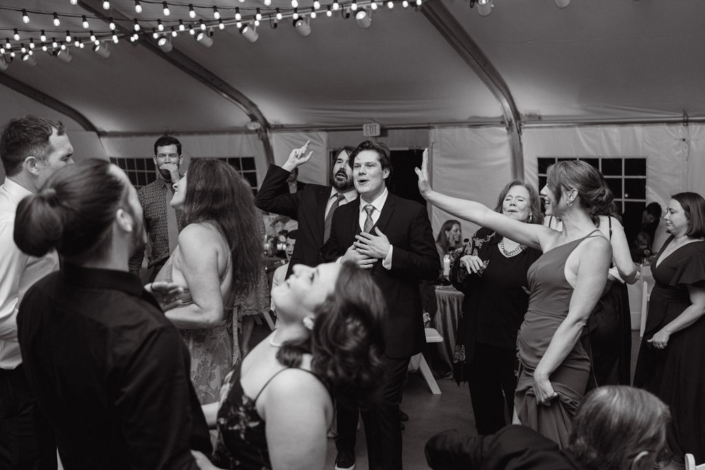 Black-and-white photo of lively wedding reception dancing under café lights at Hudson Gardens in Colorado.