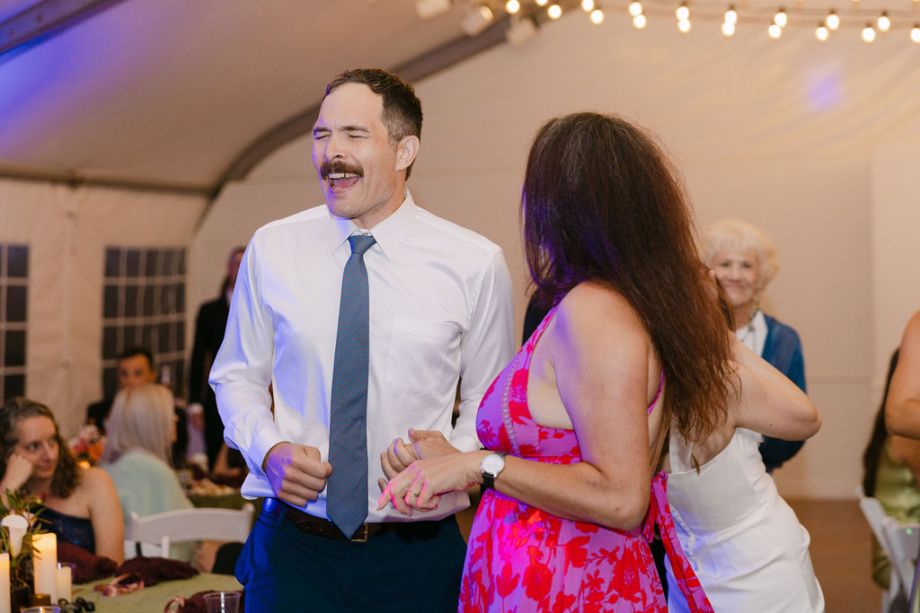 Guests smiling and dancing during an elegant Colorado wedding reception under string lights.