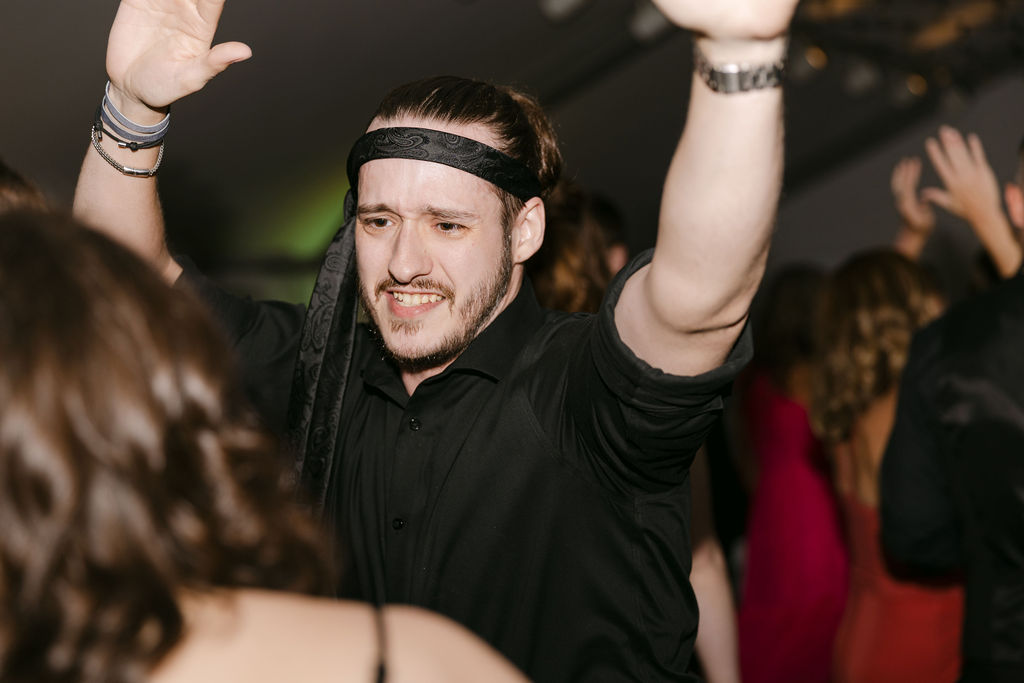 Wedding guest dancing with raised hands during an energetic Hudson Gardens reception.