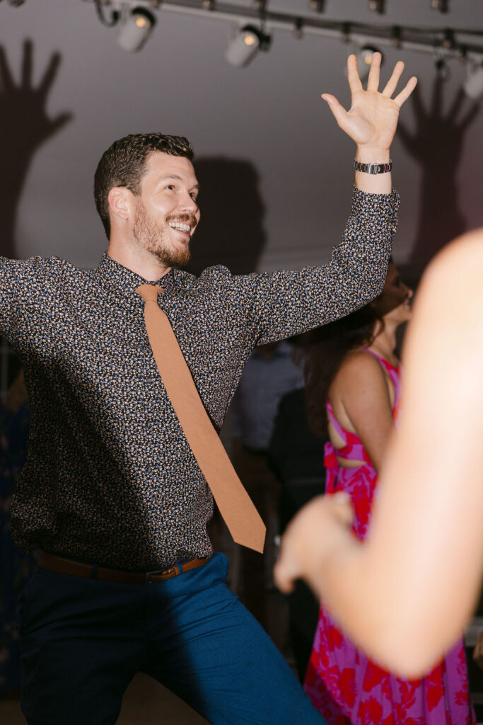 Wedding guest enthusiastically dancing during the celebration at Hudson Gardens.