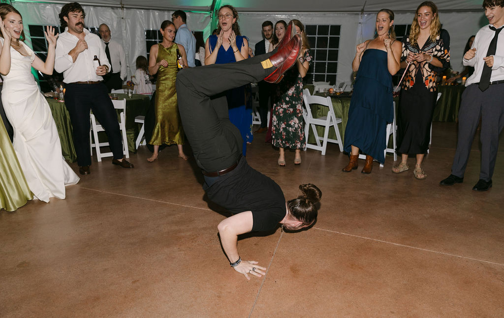 Talented guest performing a breakdance move on the dance floor during a Hudson Gardens wedding reception.