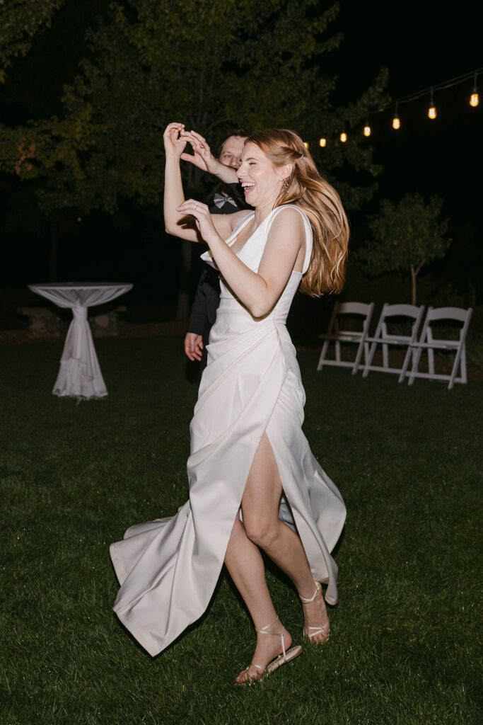 Bride dancing outdoors under string lights during a nighttime celebration at Hudson Gardens.