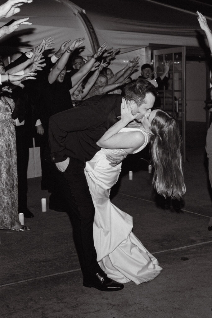 Black-and-white photo of bride and groom sharing a dramatic dip kiss during their grand exit at Hudson Gardens in Colorado.