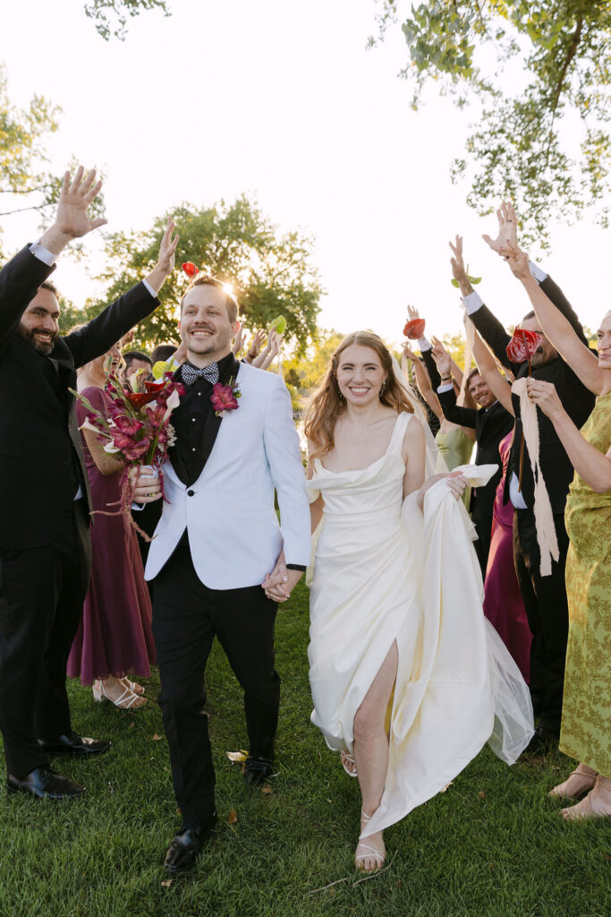 Bride and groom’s grand exit moment with bridal party cheering during a garden wedding in Colorado.