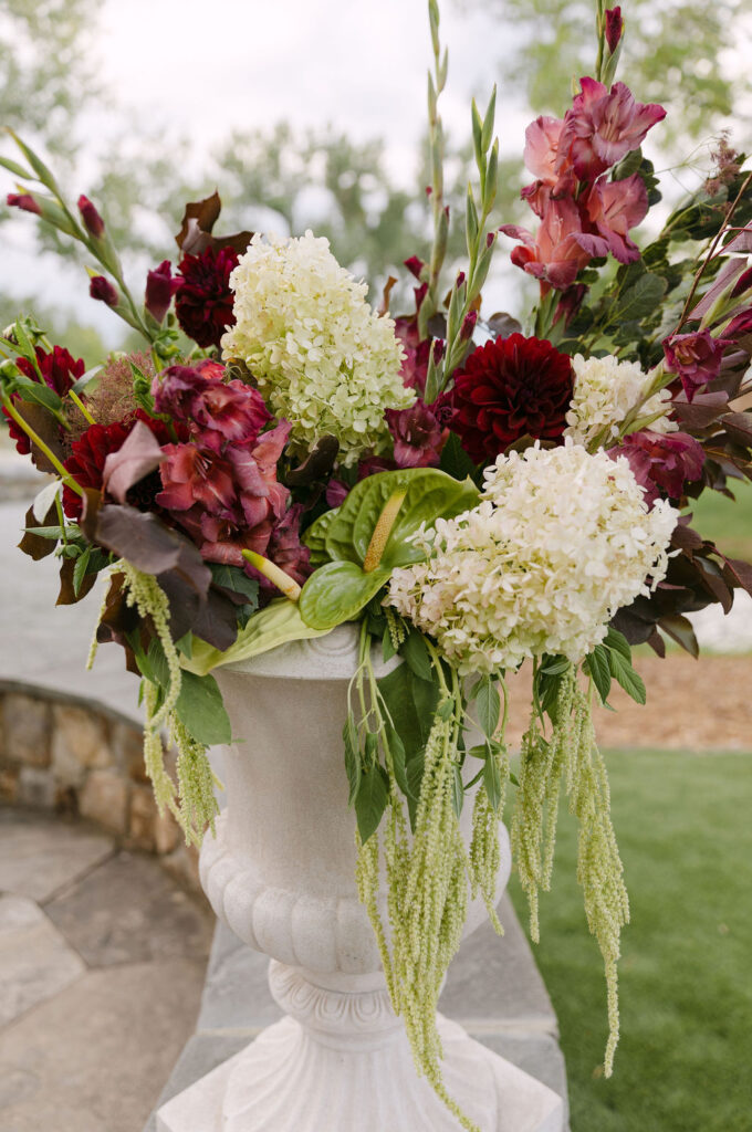 Floral urn with hydrangea and deep-red blooms at an elegant Colorado outdoor wedding ceremony.