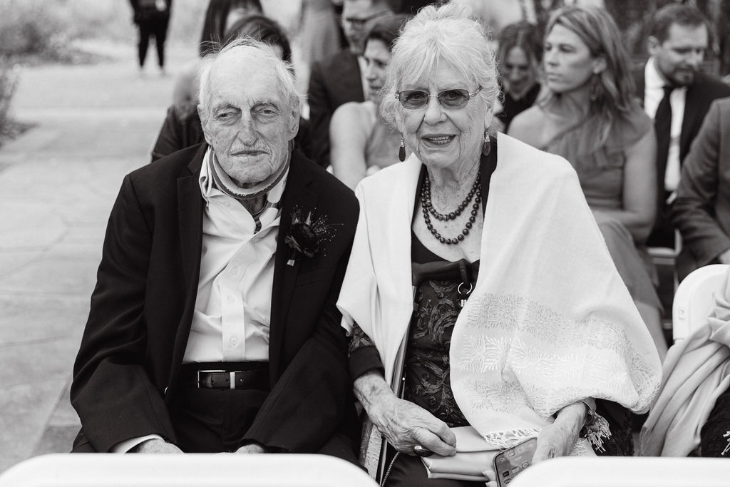 Candid black-and-white of grandparents seated at a luxury Colorado wedding ceremony.
