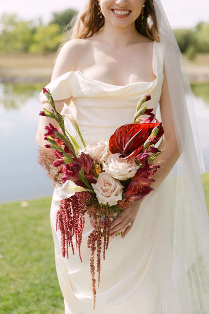 Bridal bouquet with deep red and blush florals, luxury wedding flowers for a high-end Colorado garden ceremony.