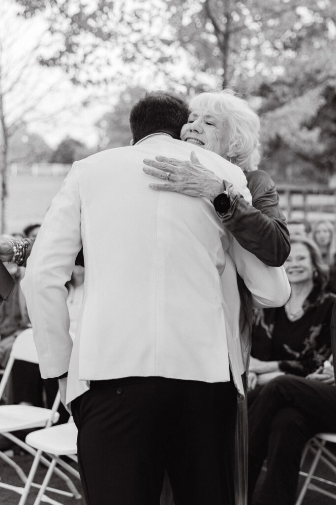 Black-and-white candid of the groom hugging a family member before a Colorado wedding ceremony.