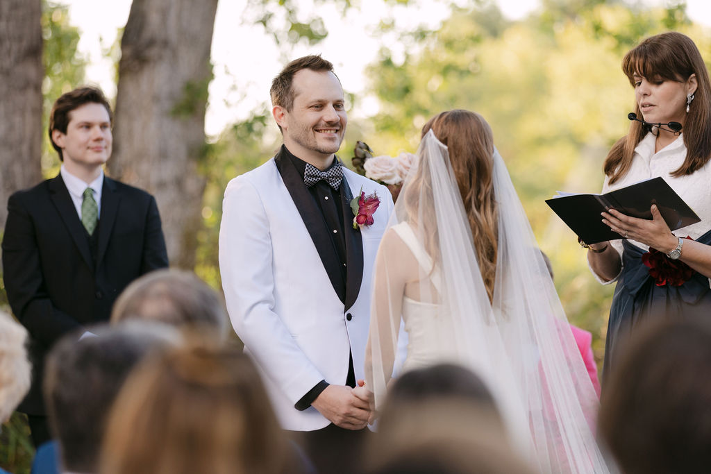 Groom smiling during ceremony with groomsmen behind him at a luxury Colorado wedding.
