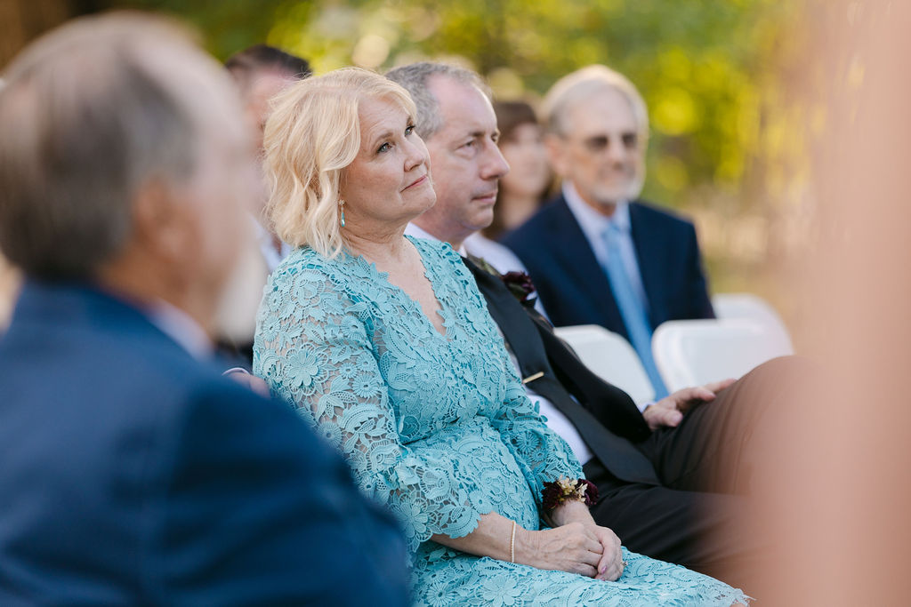 Mother of the bride watching the garden ceremony at Hudson Gardens in Colorado.