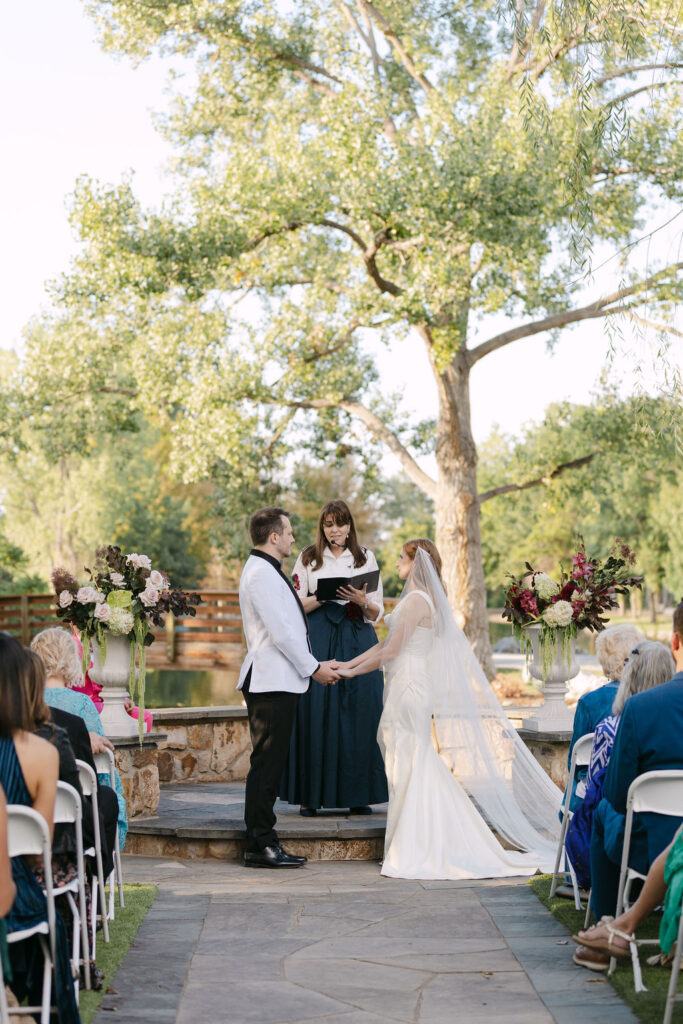 Wide ceremony shot of couple exchanging vows in front of large tree at Hudson Gardens wedding venue.