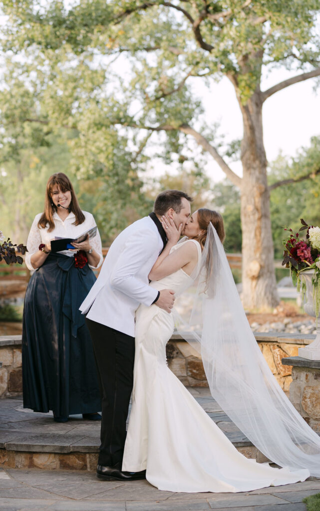 Bride and groom sharing their first kiss at the altar during a Hudson Gardens outdoor ceremony.