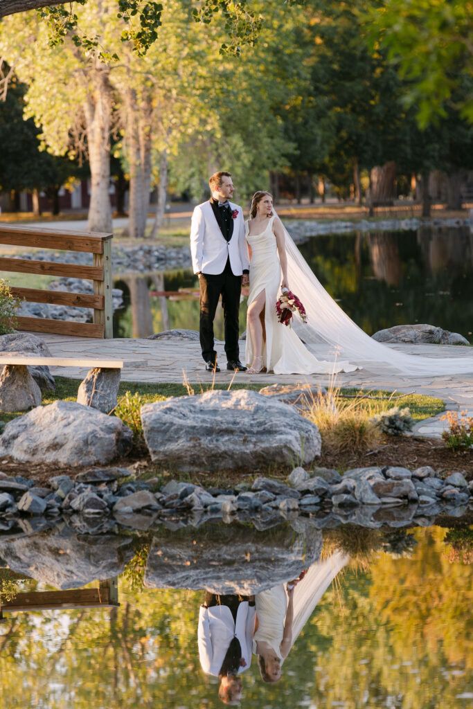 Bride and groom standing on a wooden bridge reflecting in the pond at Hudson Gardens during golden hour.