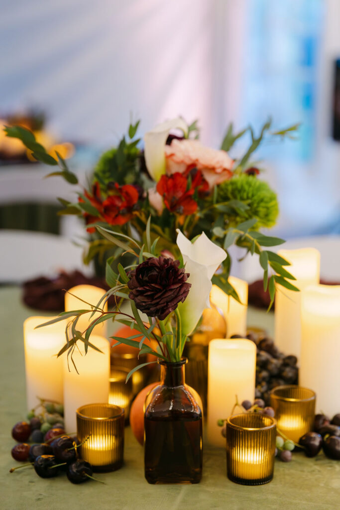 Romantic candlelit centerpiece with grapes, florals, and gold votives at a high-end Hudson Gardens wedding reception.