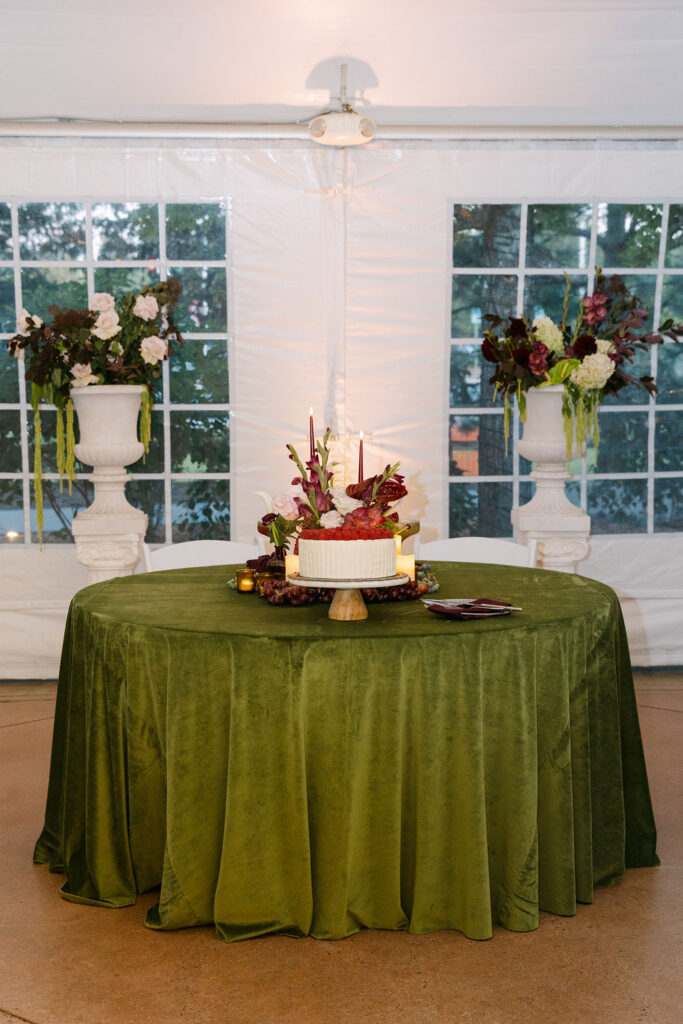 Wedding cake table with florals, candles, and fine-art styling at Hudson Gardens in Colorado.