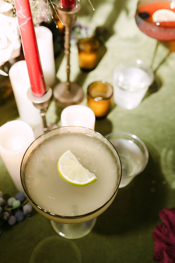 Close-up of lime-garnished cocktail on reception table during a Colorado garden wedding.