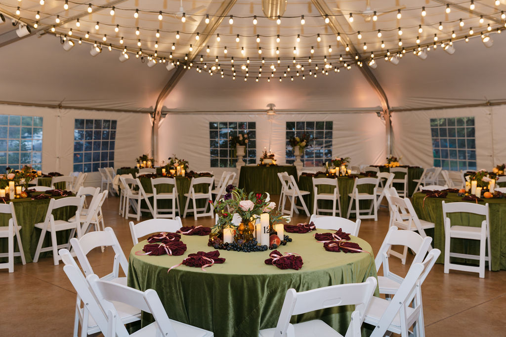 Reception tent at Hudson Gardens decorated with string lights and green velvet linens for an upscale Colorado wedding reception.