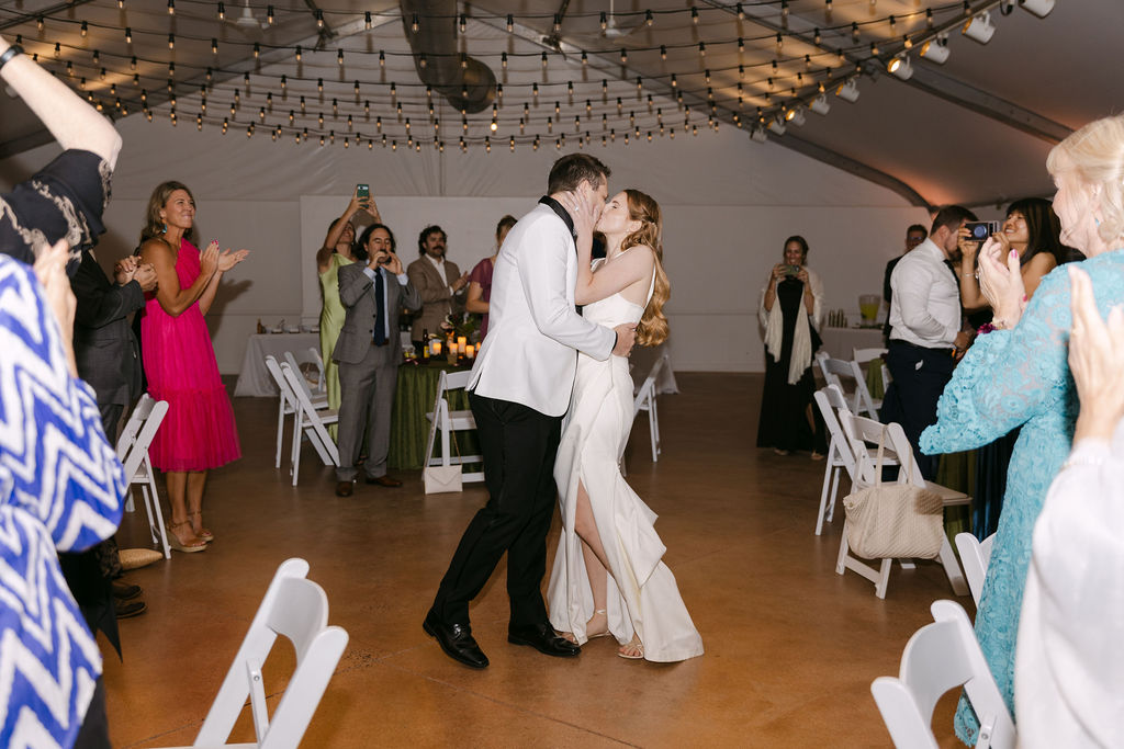 Bride and groom sharing their first dance under string lights in an elegant Colorado wedding tent.