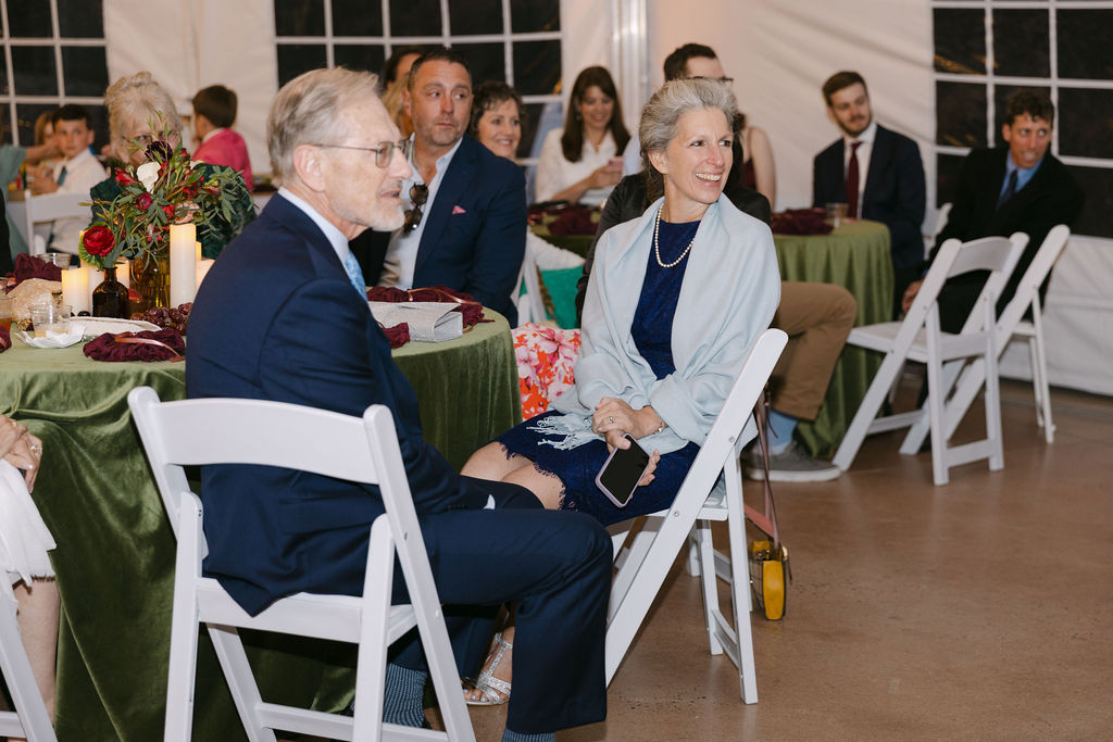 Guests listening to heartfelt speeches during an elegant tented reception at Hudson Gardens.