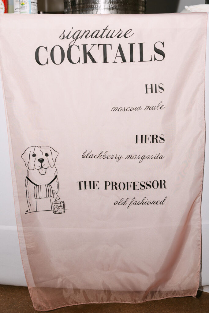 Custom signature cocktail sign featuring his-and-hers drinks and the couple’s dog illustration.