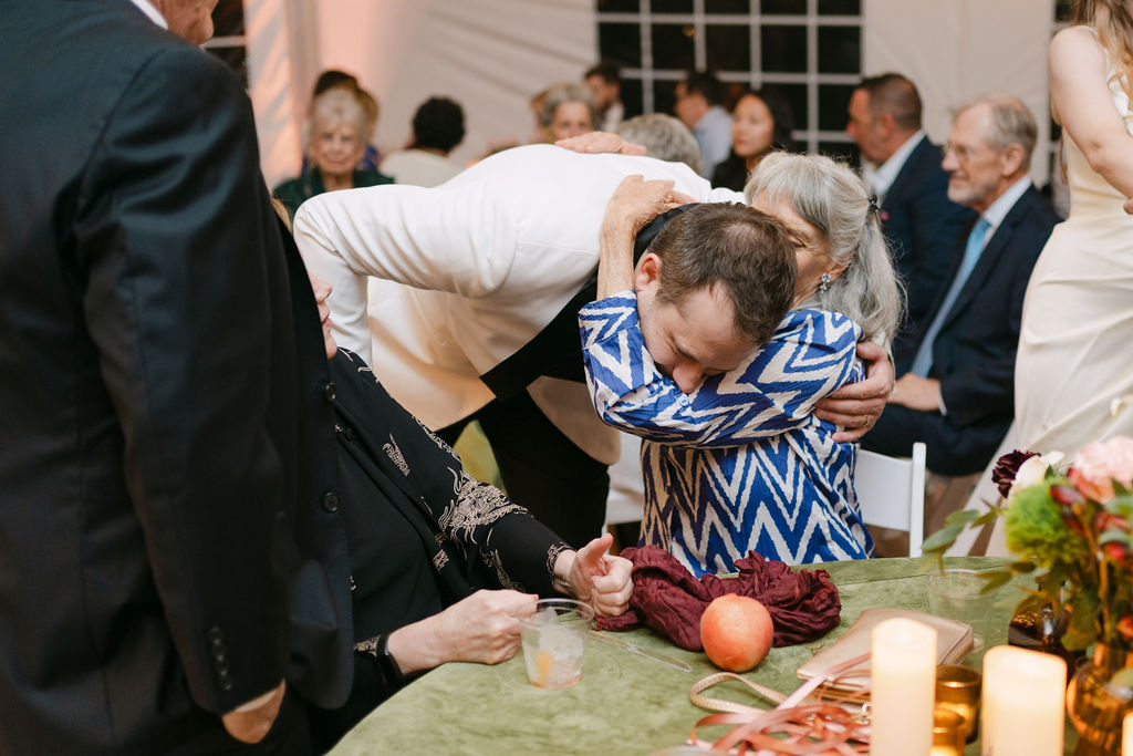Groom hugging a family member during cocktail hour at an elegant Colorado garden wedding.