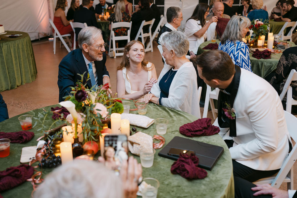 Bride smiling and chatting with older family members during reception at Hudson Gardens in Littleton, Colorado.