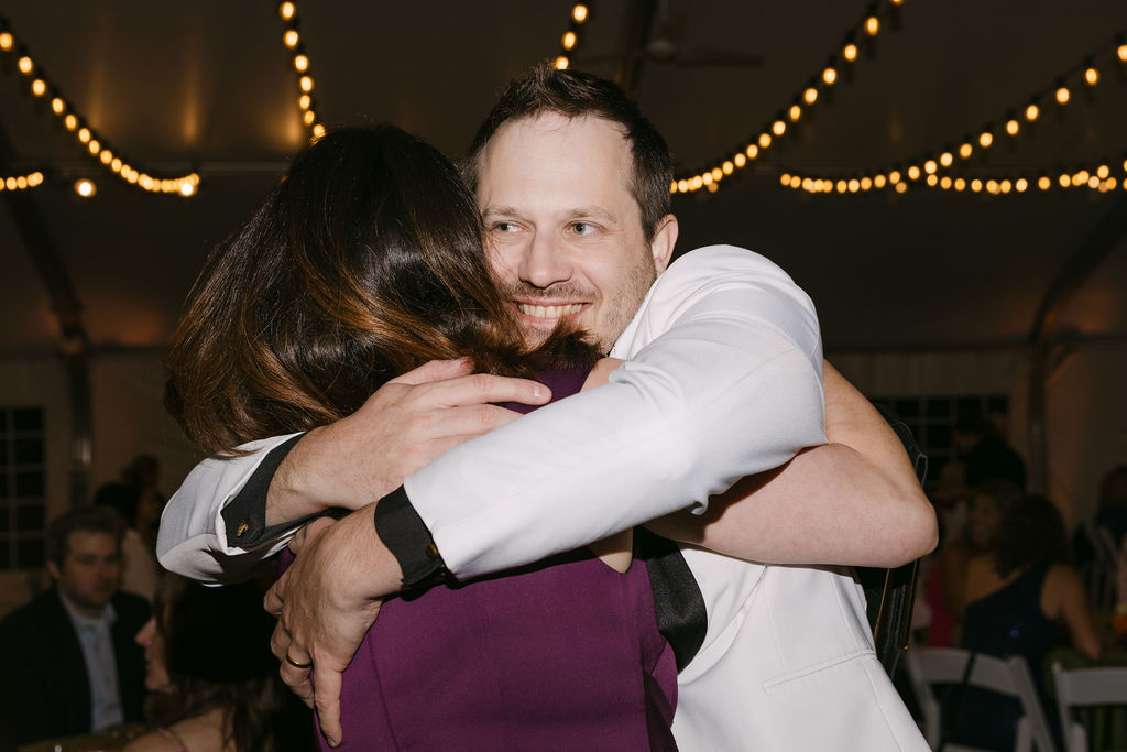 Groom hugging a guest warmly during the reception at Hudson Gardens wedding venue.