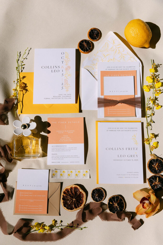 Mauve, yellow and orange wedding invitation suite with dried fruit styled elegantly at a Colorado estate wedding venue