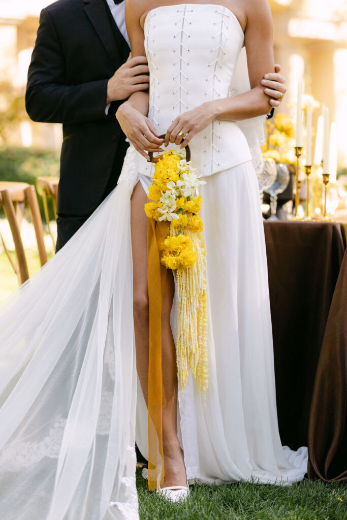 Unique and colorful bridal bouquet displayed against the bride's stylish corseted wedding dress at a luxury wedding in Colorado 