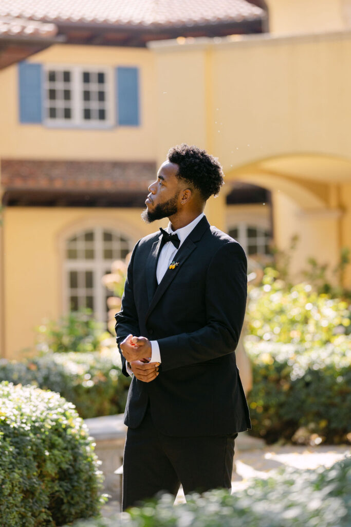 Groom posing among the greenery at Oceana's gardens for his getting ready portraits 