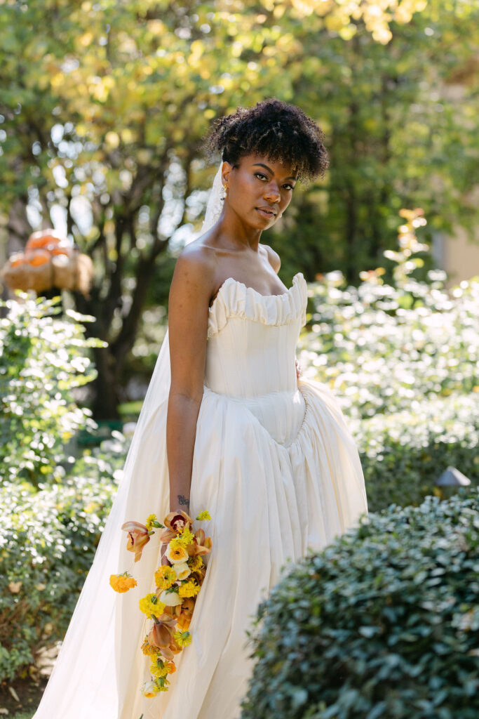 Bride posing in a vintage editorial wedding dress among the gardens at a European-inspired Colorado wedding venue 