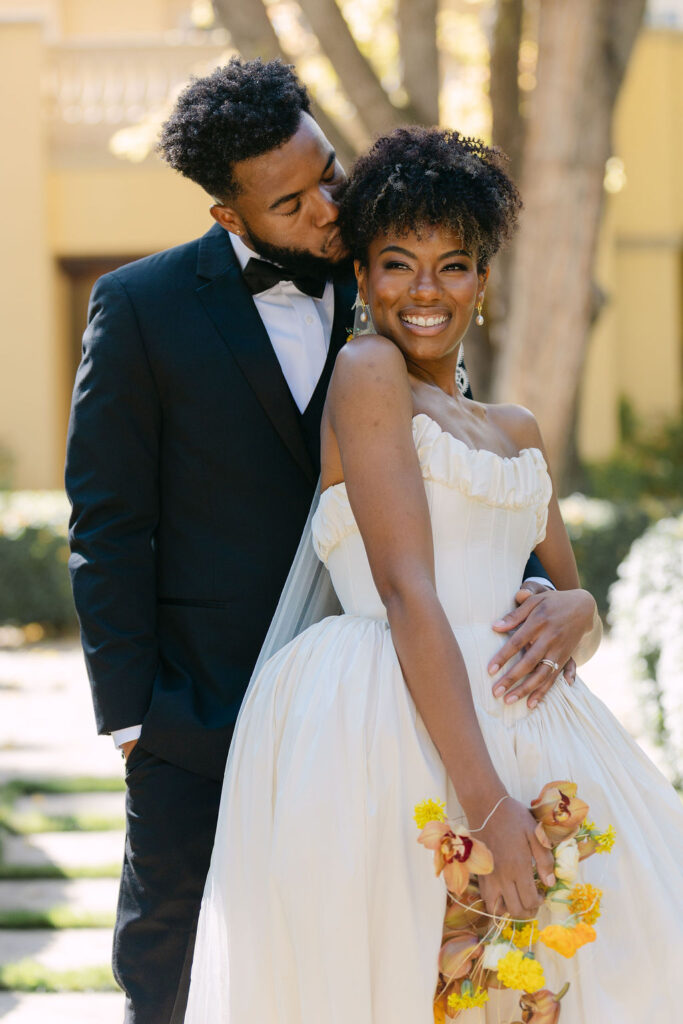 Groom kissing his bride on the cheek while she laughs for a romantic wedding portrait in Boulder, Colorado 