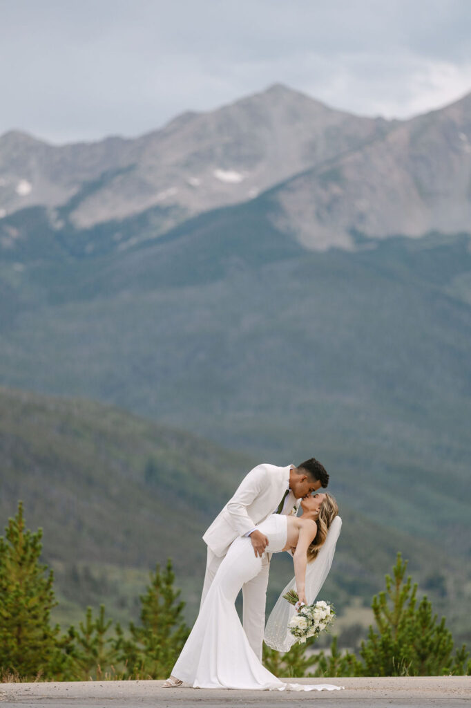 Bride and groom kissing in front of the rocky mountains at sapphire point overlook in Breckenridge, Colorado