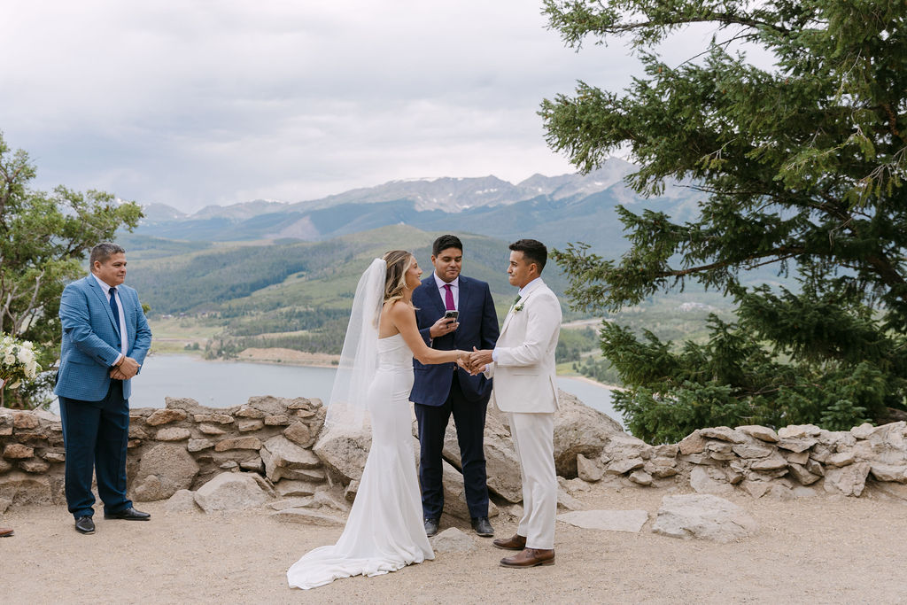 Bride and groom holding hands during their micro wedding ceremony at Sapphire Point Overlook in Dillon, Colorado