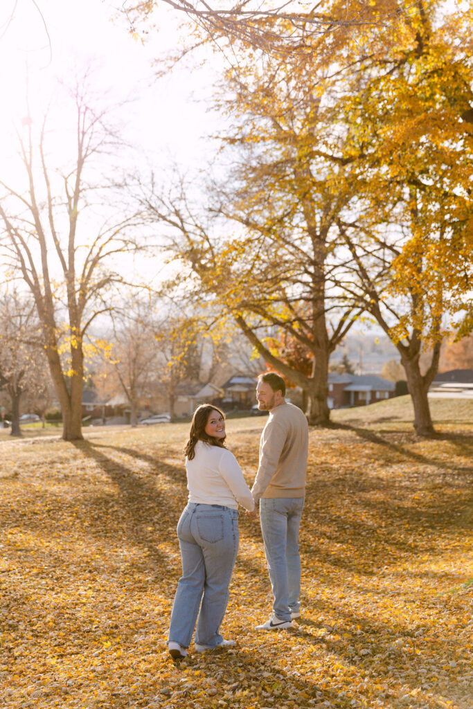Couple standing together under fall trees during Denver engagement photos at Inspiration Point Park.