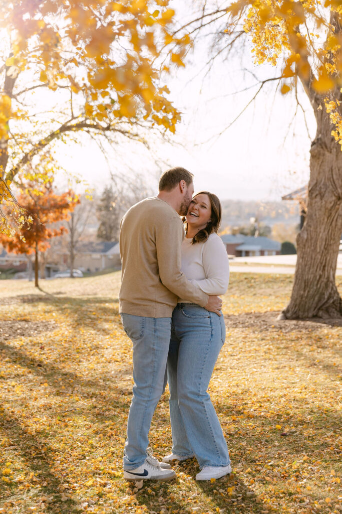 Couple cuddling in the golden leaves at Inspiration Point Park in Denver.