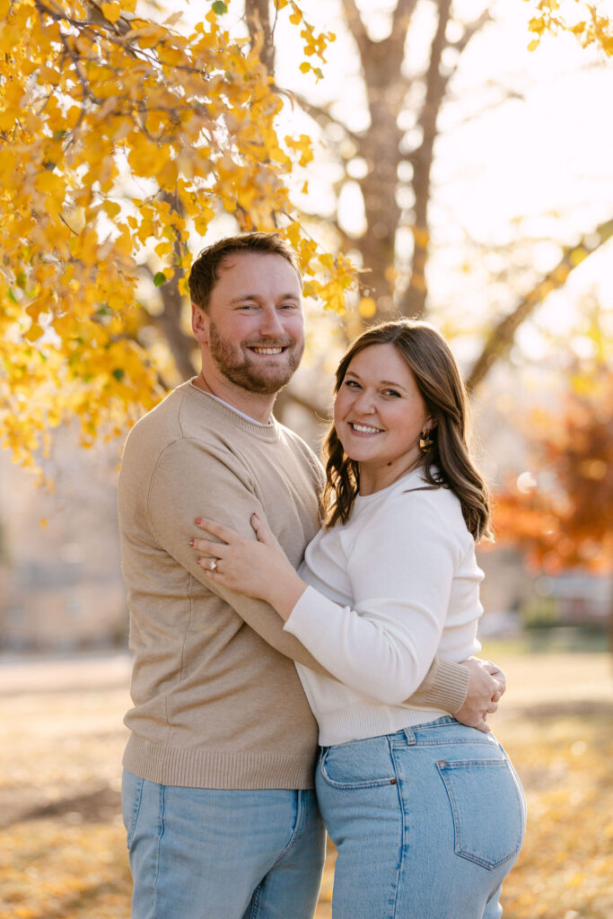 Couple smiling and holding each other during fall engagement photos at Inspiration Point Park