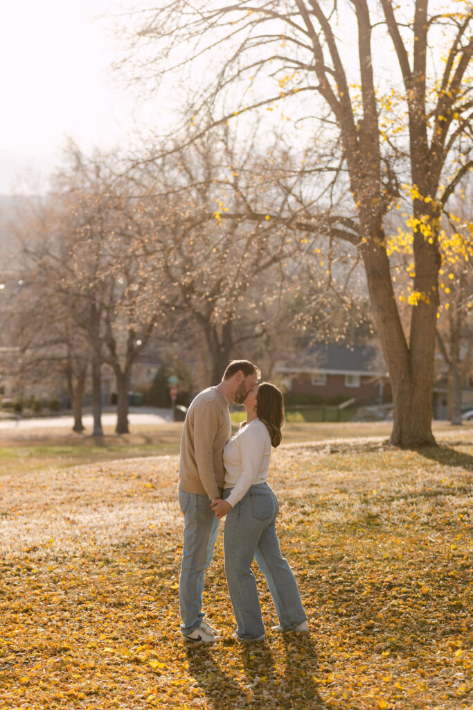 Playful moment of couple spinning under trees during fall engagement photos in Denver.