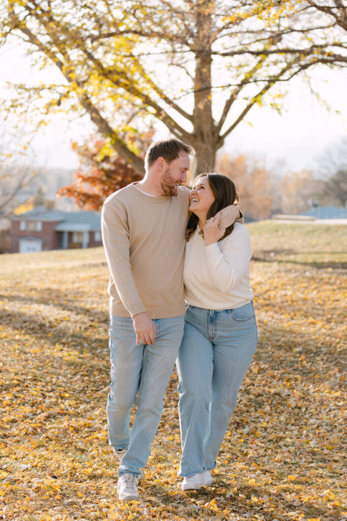 Couple walking through golden fall leaves during their Inspiration Point Park engagement session in Denver.