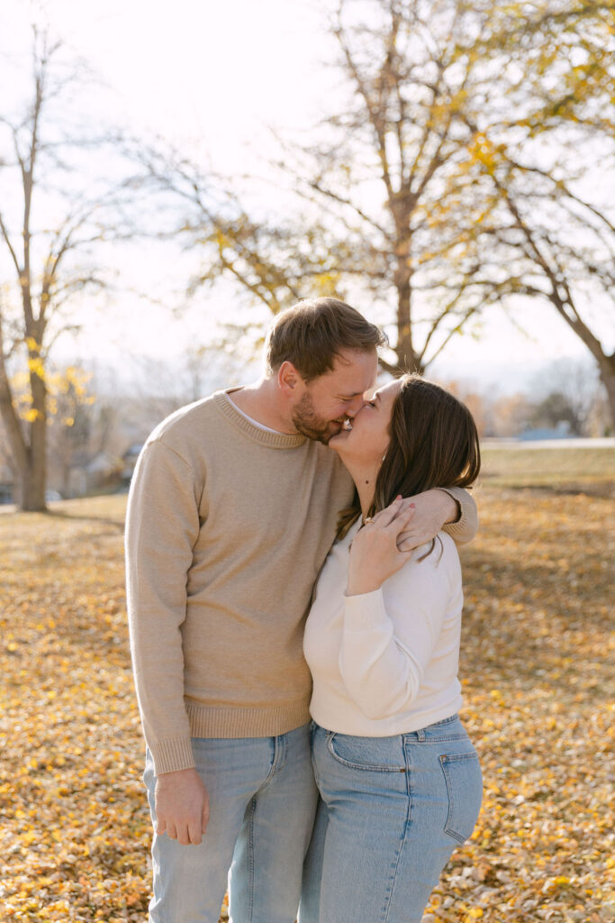 Couple kissing during their Denver engagement photos at Inspiration Point Park surrounded by fall trees.