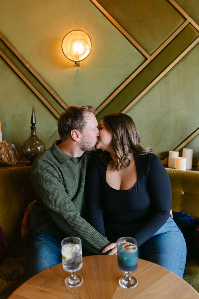 Couple kissing in a booth during their Denver engagement photos 