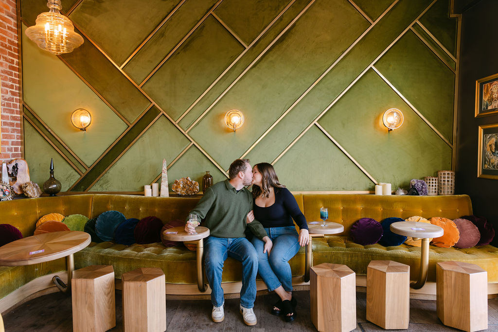 Couple kissing in a cocktail bar in denver during their engagement photos at Honey Elixir Bar