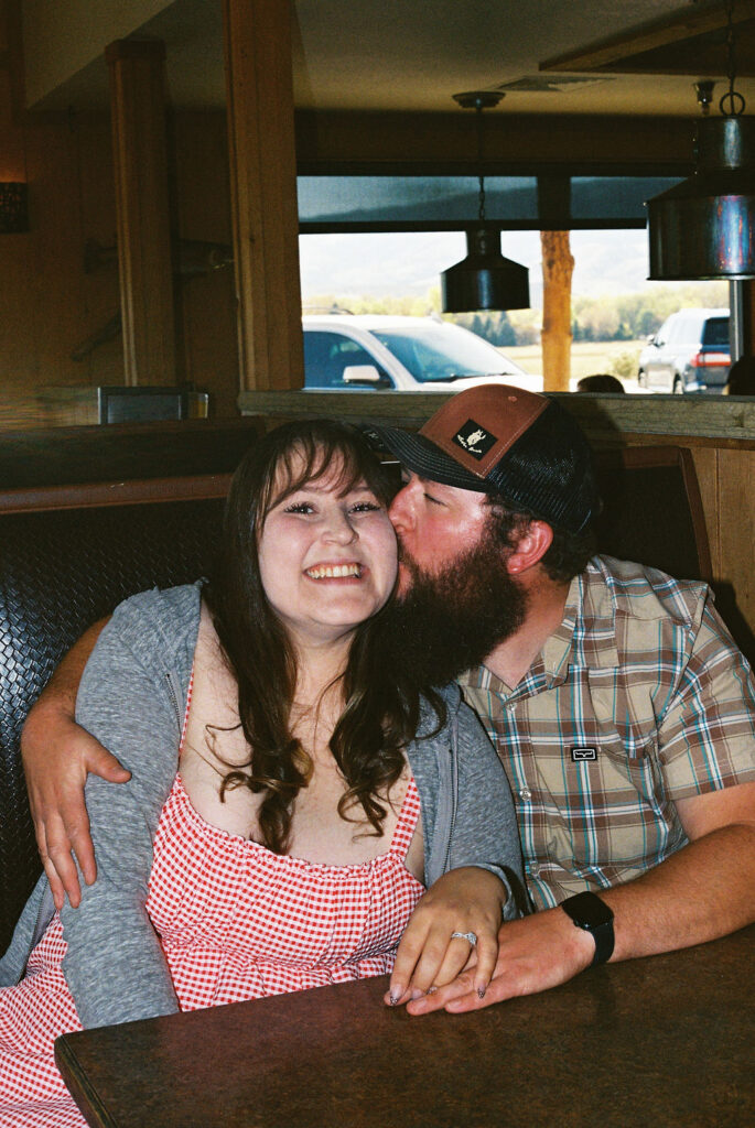 Couple laughing together in a Vern’s Place booth during their Northern Colorado engagement session.