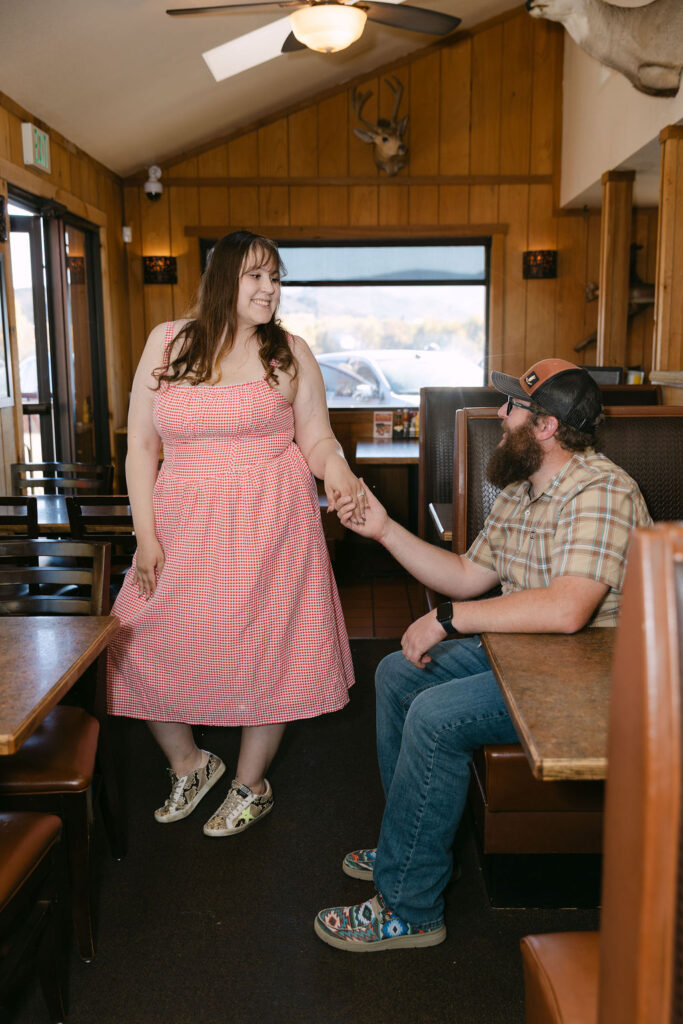Partner helping the other step out of the diner booth during their Vern’s Place engagement session