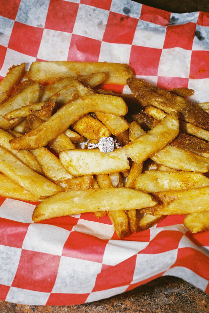 Engagement ring sitting on a pile of seasoned fries at Vern’s Place, photographed on 35mm film by a Colorado film photographer.