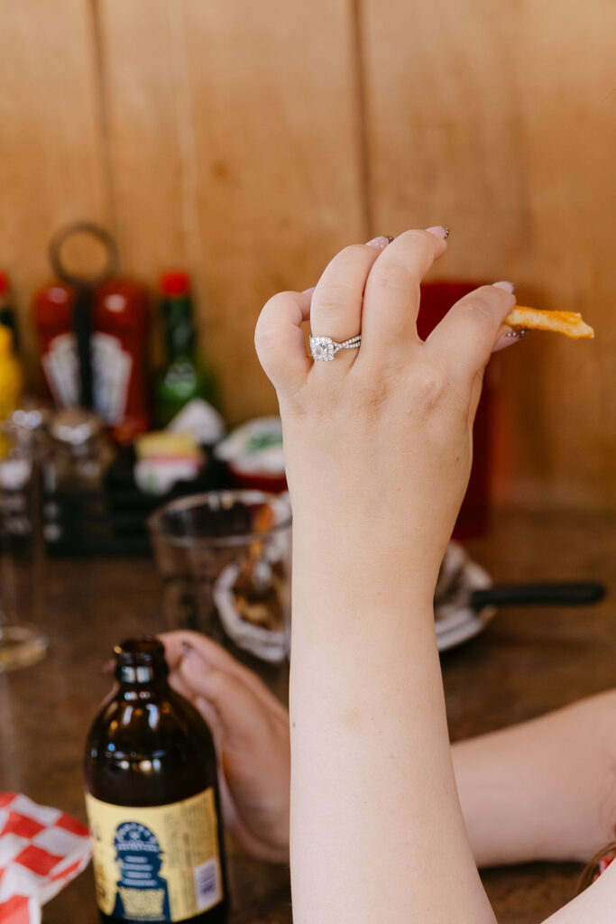 Close-up of engagement ring as the bride-to-be playfully holds a French fry at Vern’s Place.