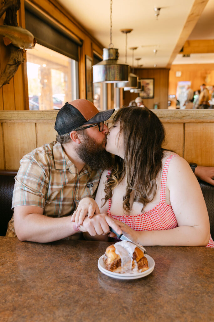 Couple kissing over their cinnamon roll during their Vern’s Place engagement session