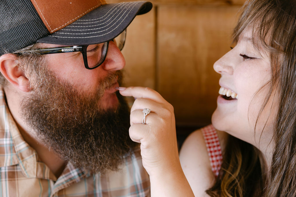 Close-up of bride-to-be feeding her partner a piece of cinnamon roll during their playful Vern’s Place diner engagement photos