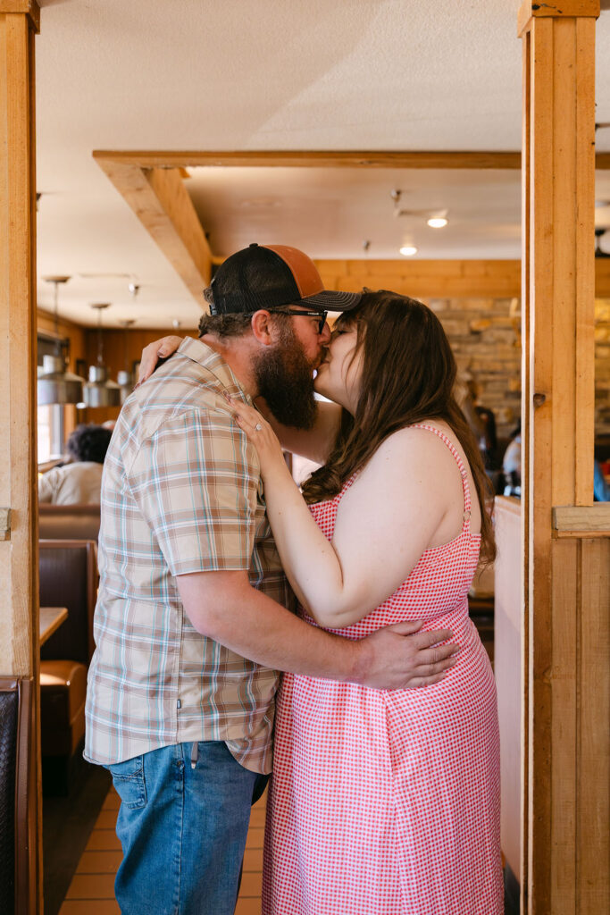 Couple sharing a kiss inside Vern’s Place during their Northern Colorado diner engagement photos